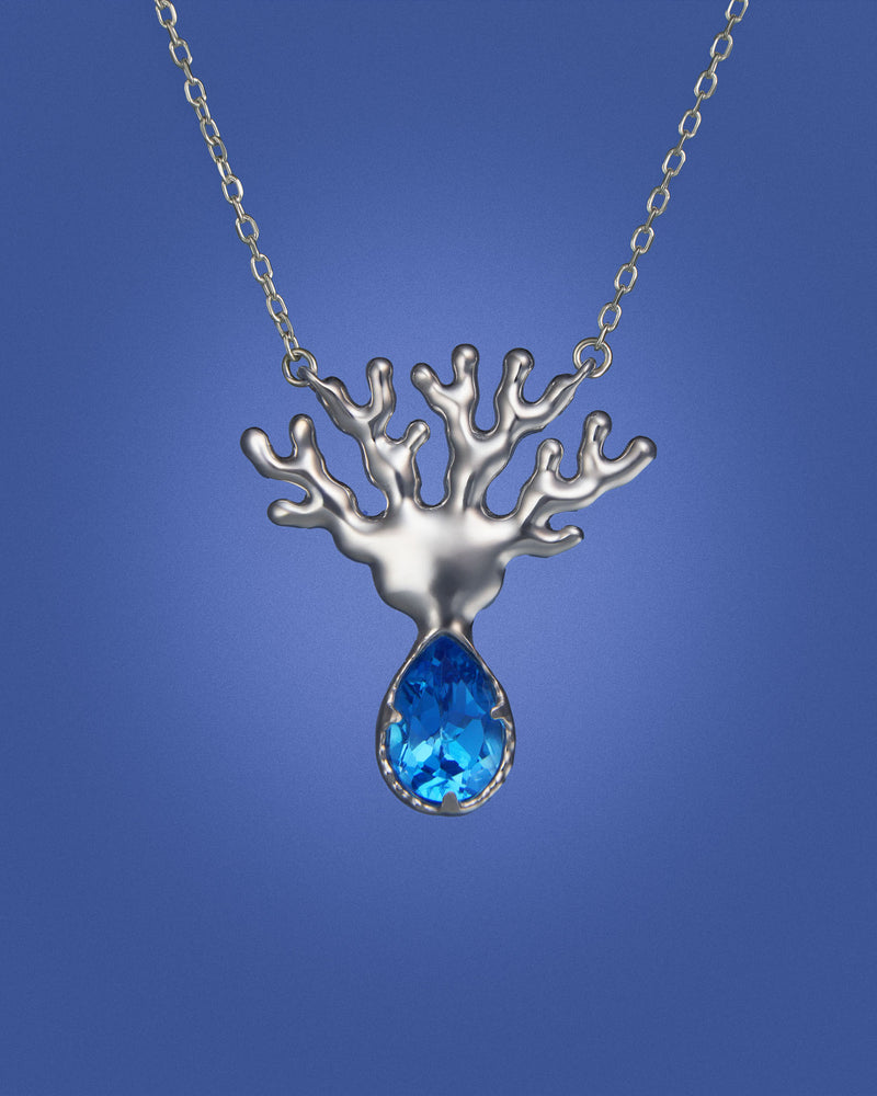 Silver coral-shaped pendant with a blue topaz gemstone on a blue background